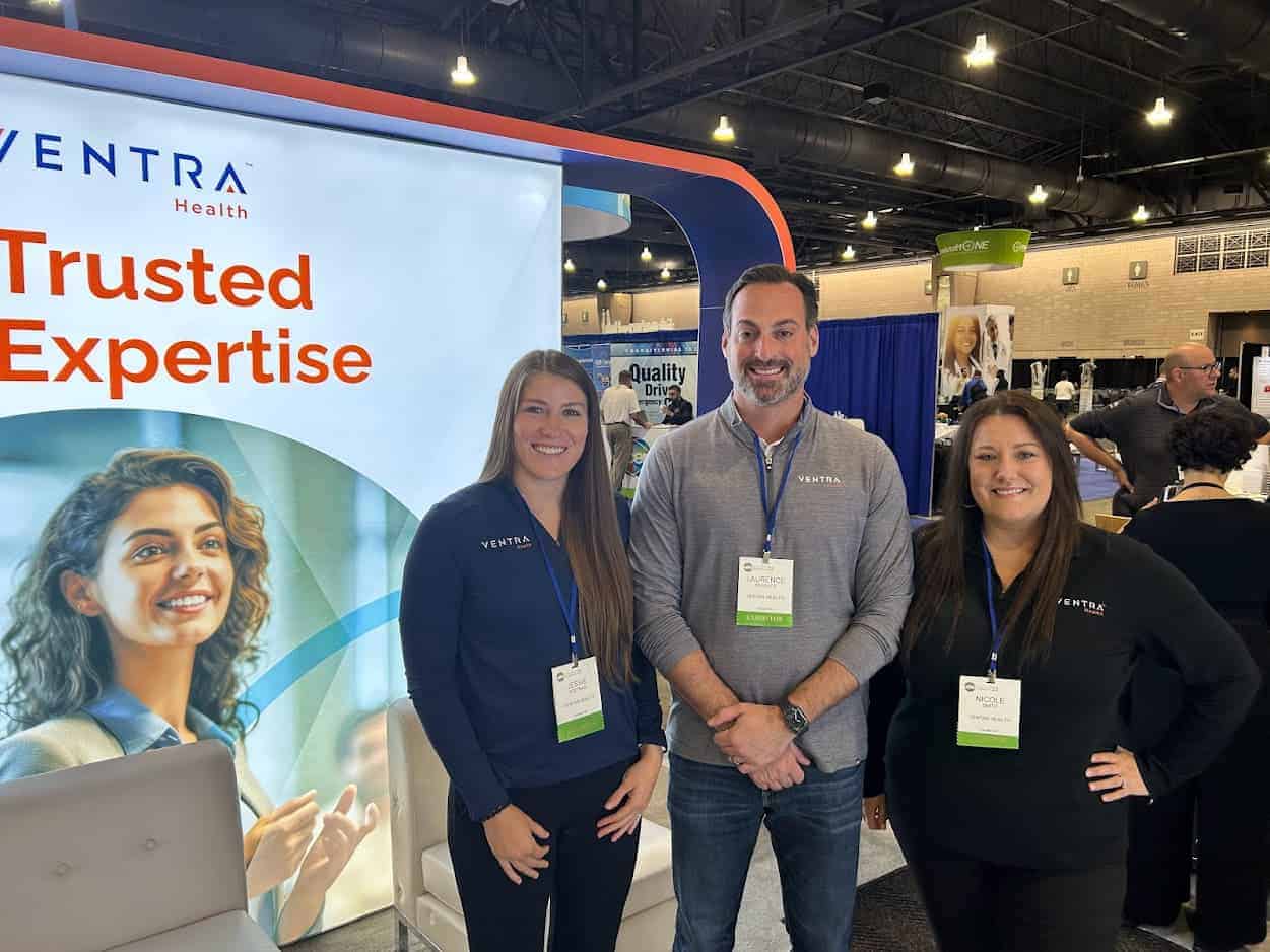 Ventra Health team members at a conference booth with banner.