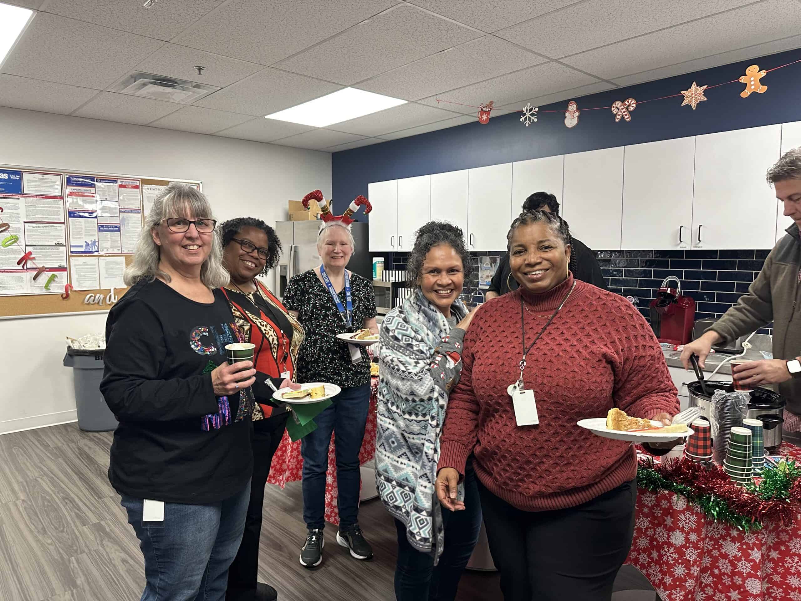 Group of diverse employees celebrating holiday in office kitchen.