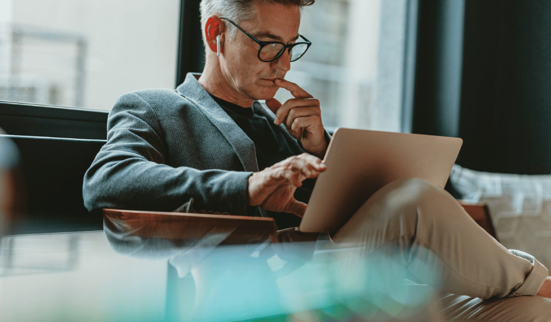 Business professional working on a laptop in a modern office setting.