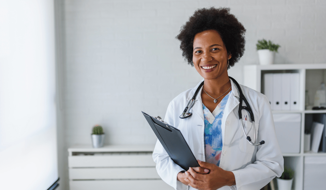 Smiling female doctor holding a clipboard in a medical office.