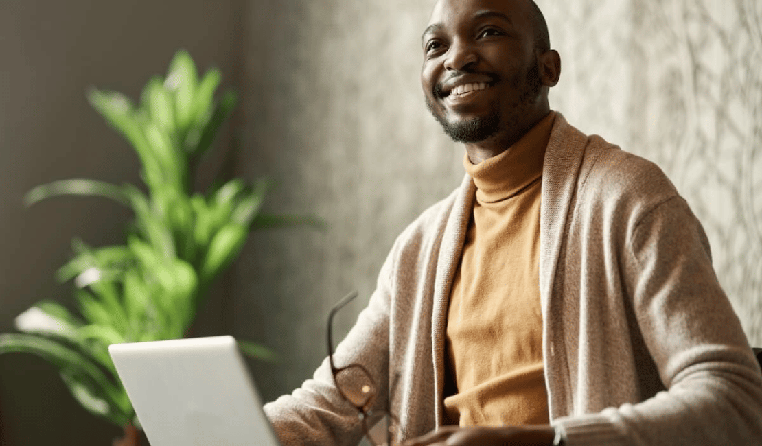 Smiling man working on a laptop in a medical office setting.